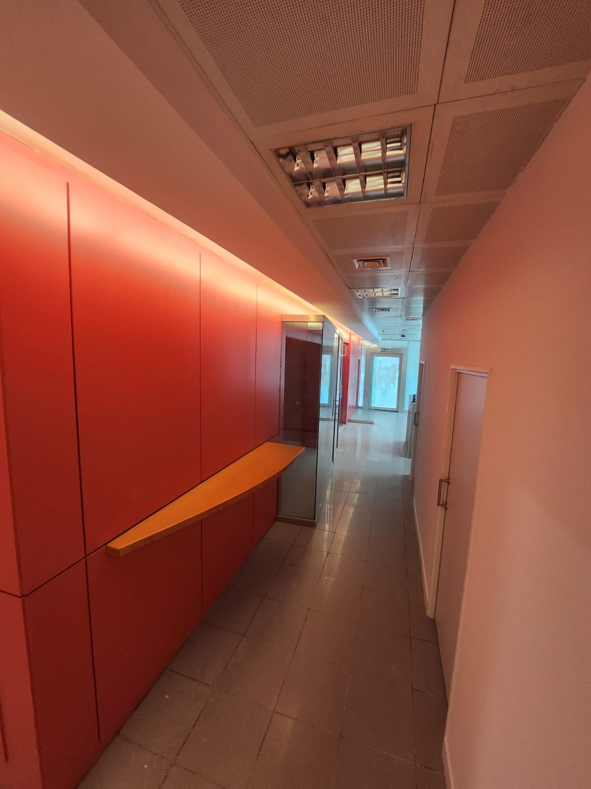 Un largo pasillo con paredes rojas y una mesa amarilla.