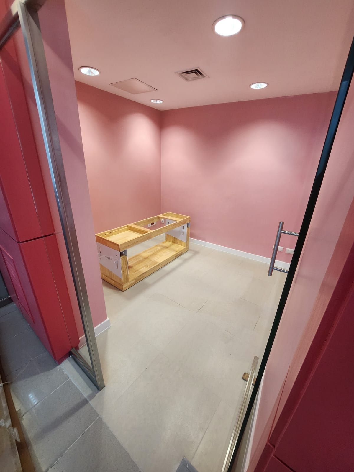 Una habitación con paredes rosas y una mesa de madera en ella.