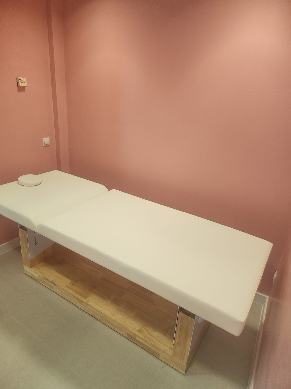 Una mesa de masaje blanca en una habitación con paredes rosas.