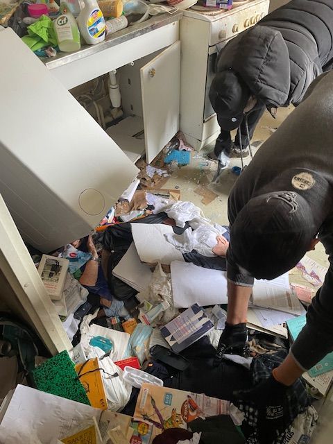 Un homme en noir ramasse des objets.