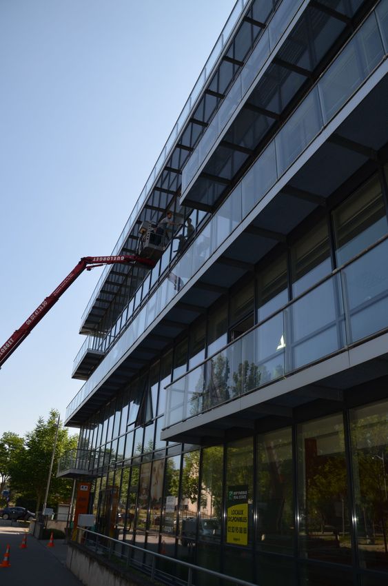 Un laveur de vitres sur une nacelle rouge.