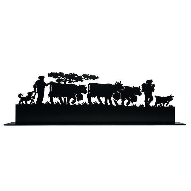 Die Silhouette eines Mannes, der neben einer Herde Kühe steht.