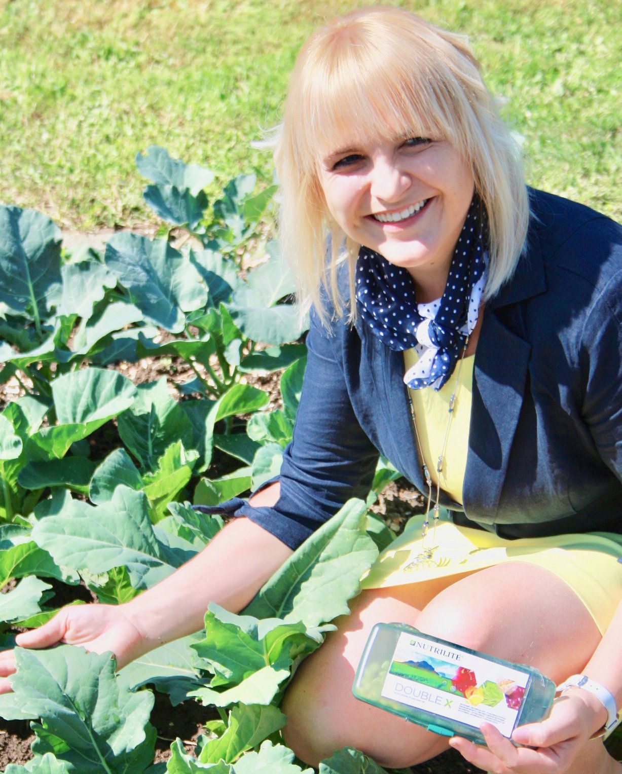 Eine Frau kniet in einem Garten und hält eine Flasche Saft