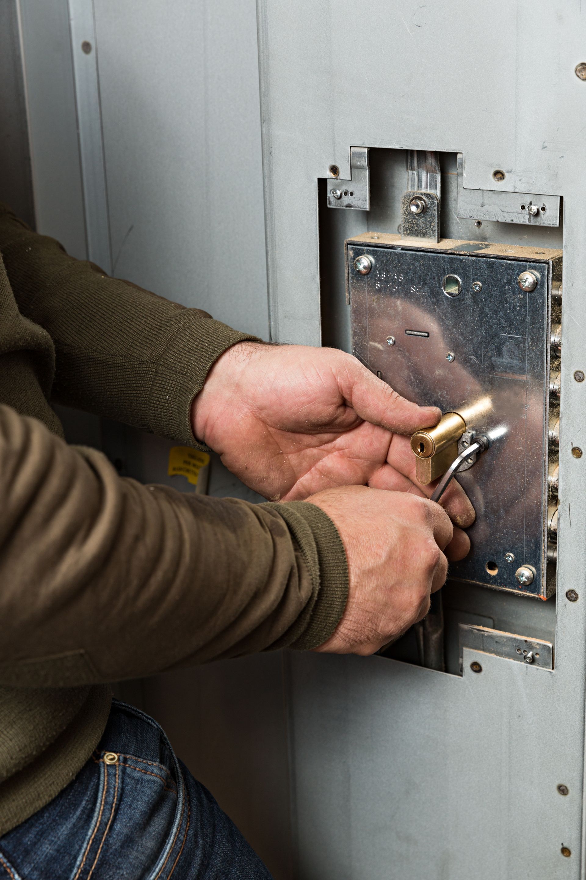 Personne utilisant des outils pour travailler sur une serrure métallique.