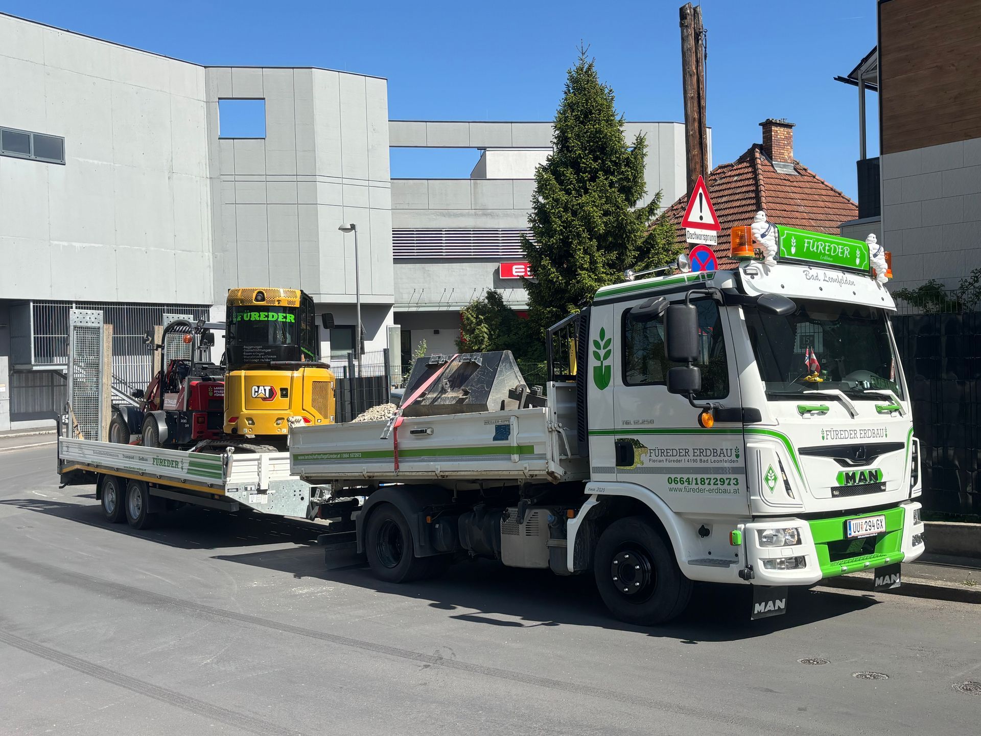 Ein grüner Traktor mäht Gras vor einem Gebäude.