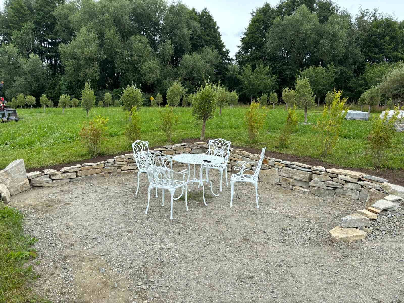 Inmitten einer Kiesfläche stehen ein Tisch und Stühle.