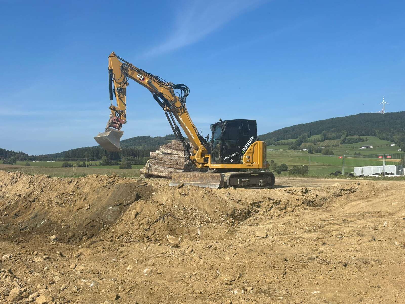 Ein gelber Bagger bewegt Erde auf einem Feld.