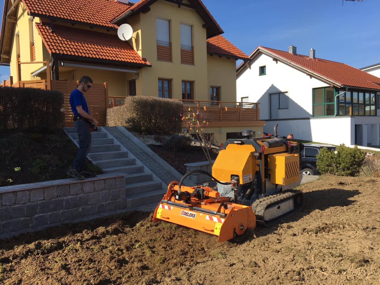 Ein Mann steht neben einem Traktor vor einem Haus