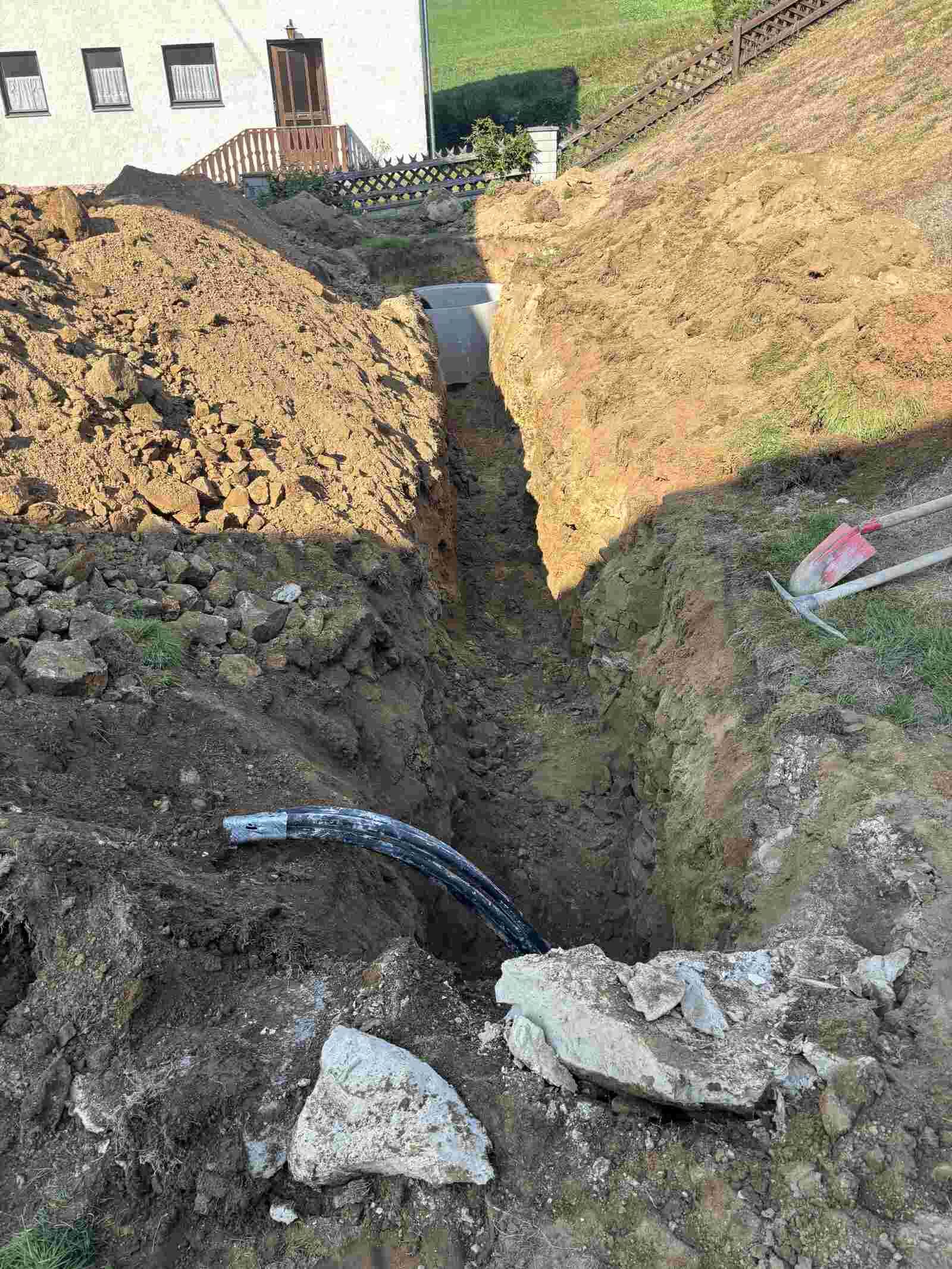 Vor einem Haus wird ein Rohr im Boden verlegt.
