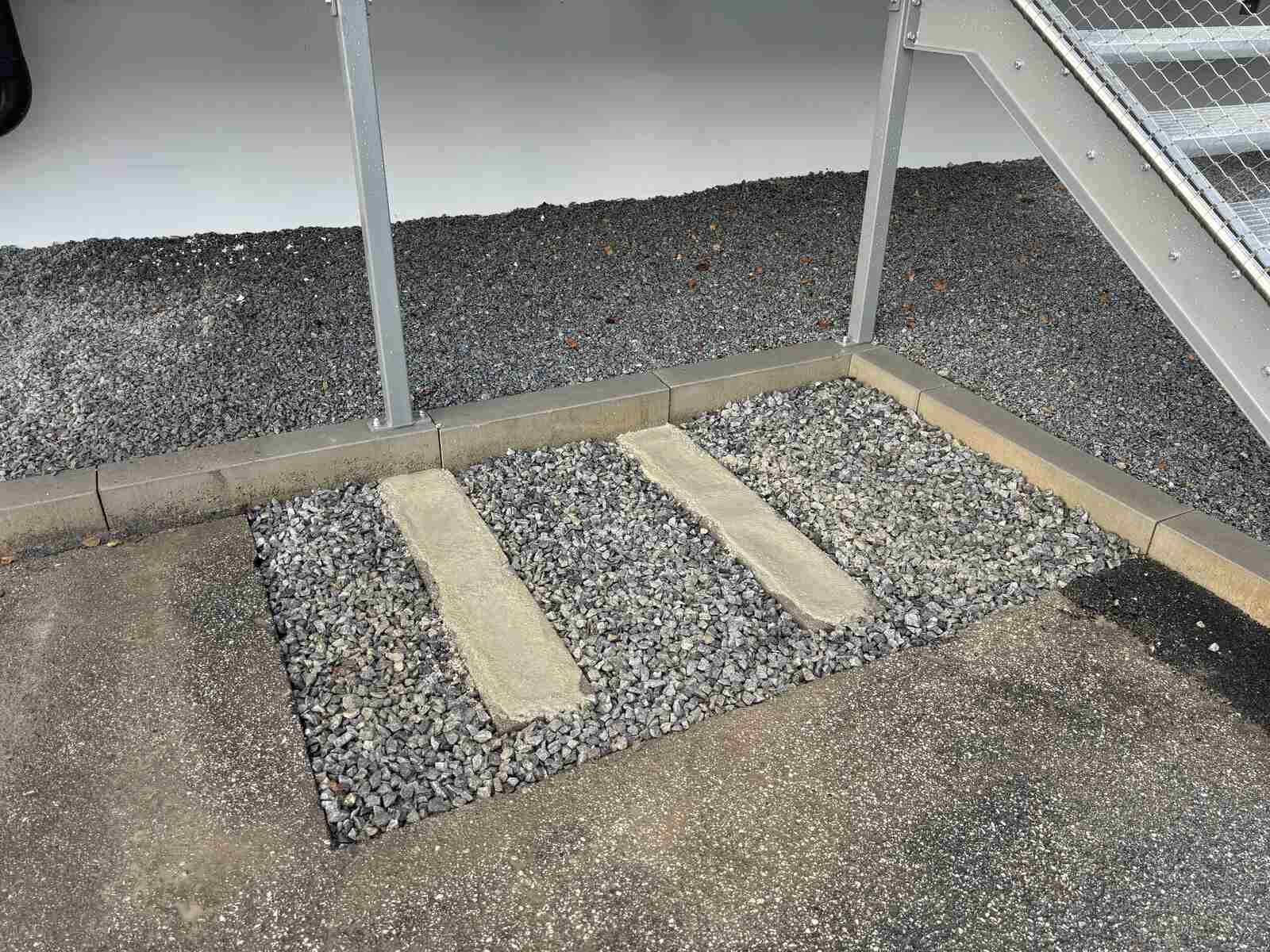 Eine Kiesfläche mit einer Treppe im Hintergrund.