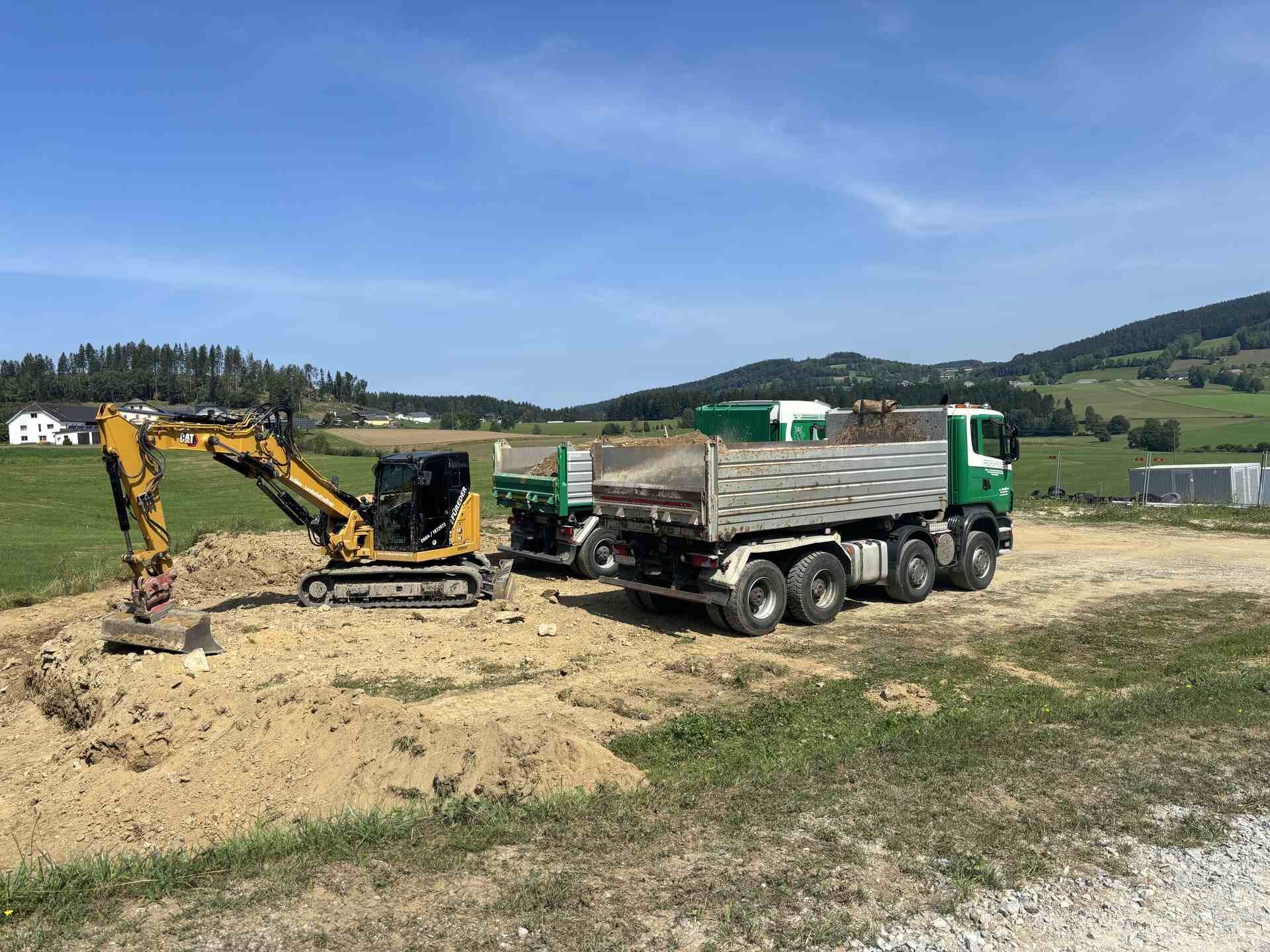 Ein Muldenkipper und ein Bagger sind auf einem Feld geparkt.