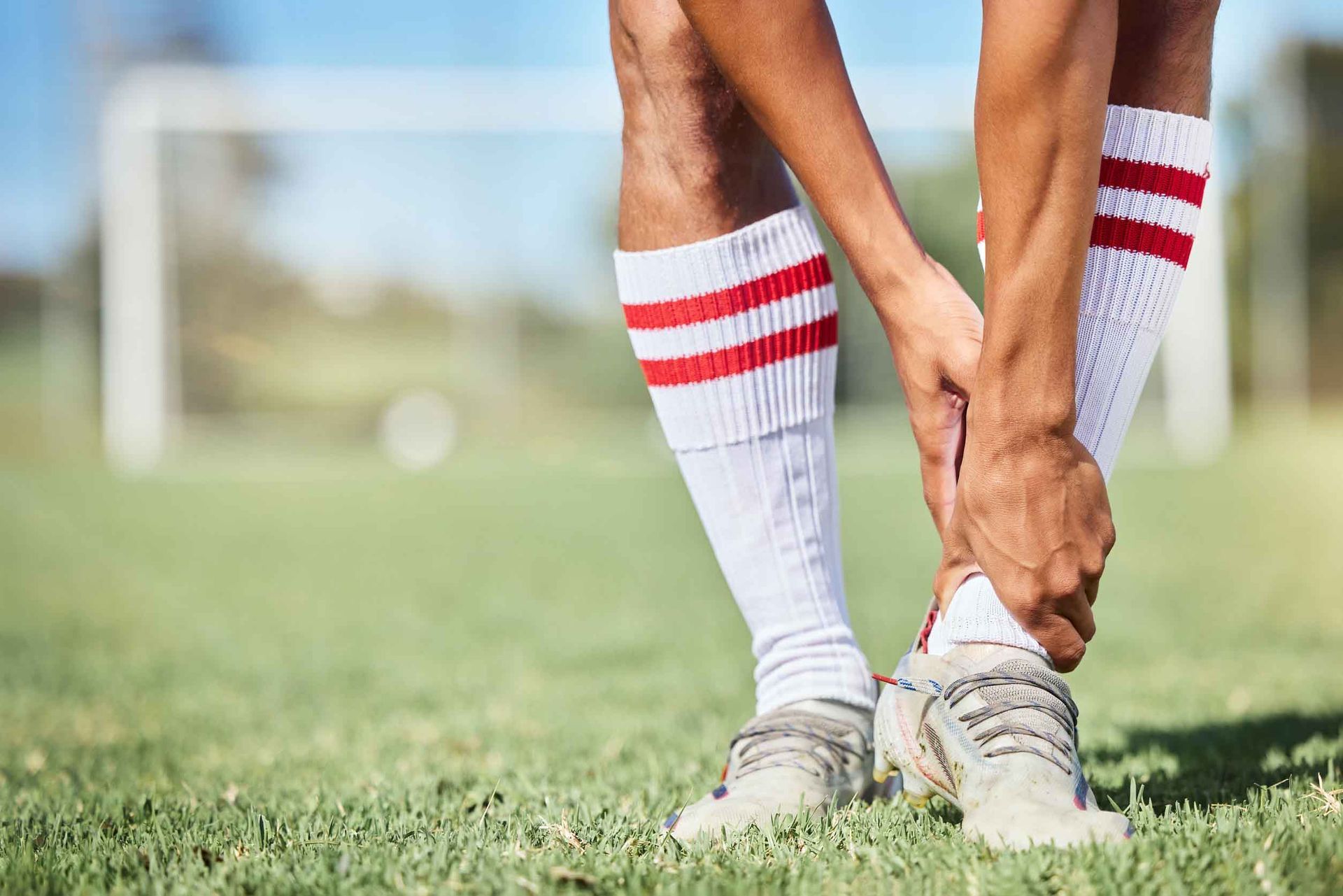 Un jugador de fútbol se está atando los calcetines en un campo.