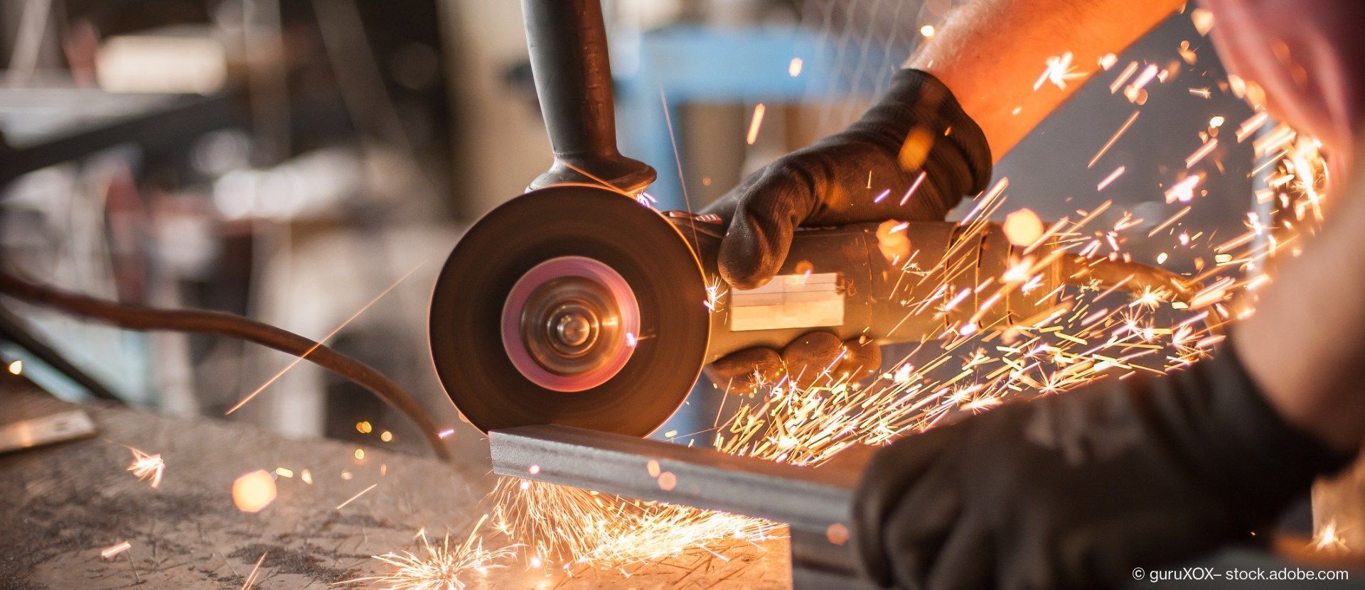 Arbeiter schneidet Metall mit einem Winkelschleifer, Funken fliegen