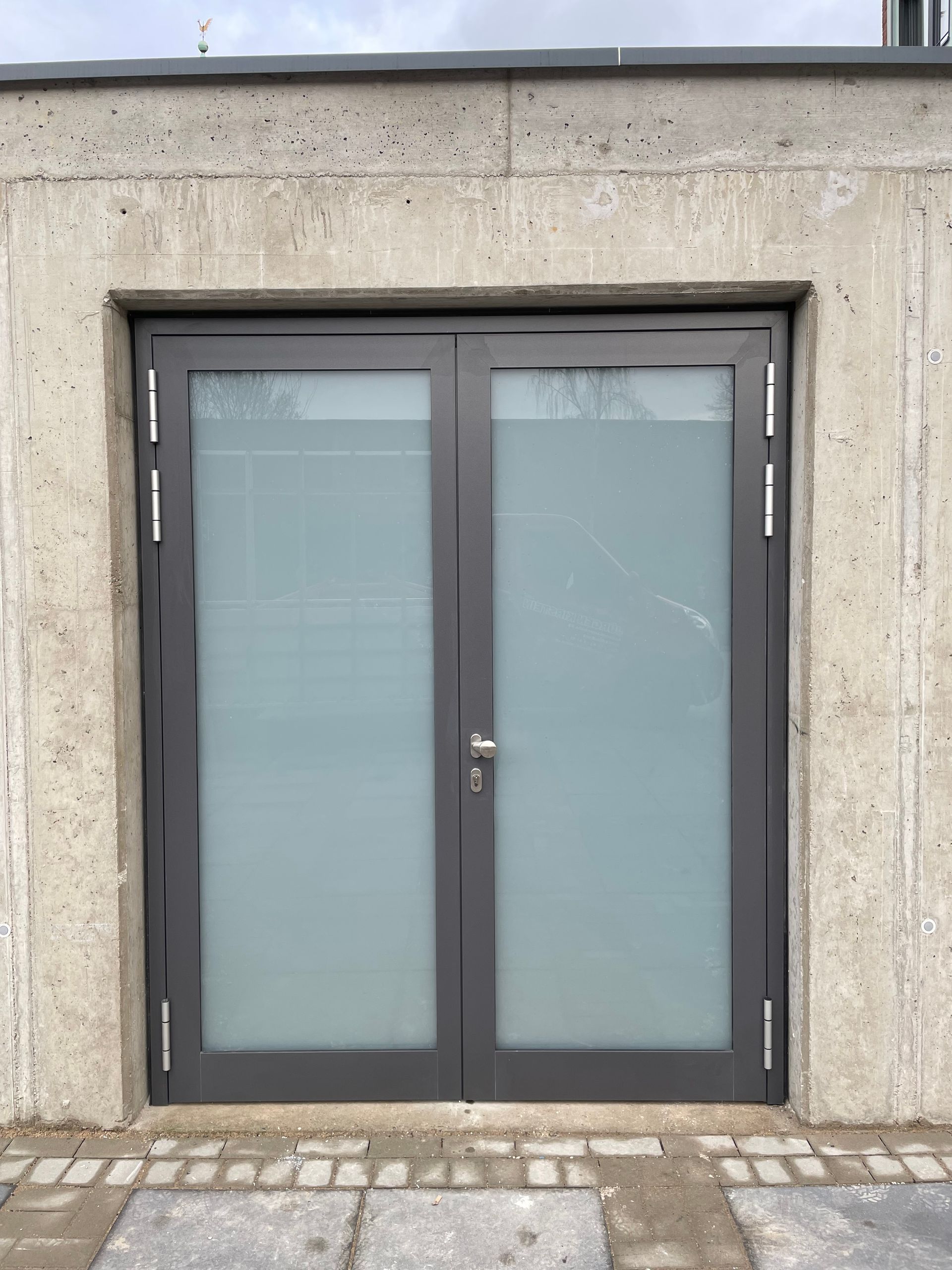 Betonfassade mit zweiflügeligem Fenster und Lichtschutz