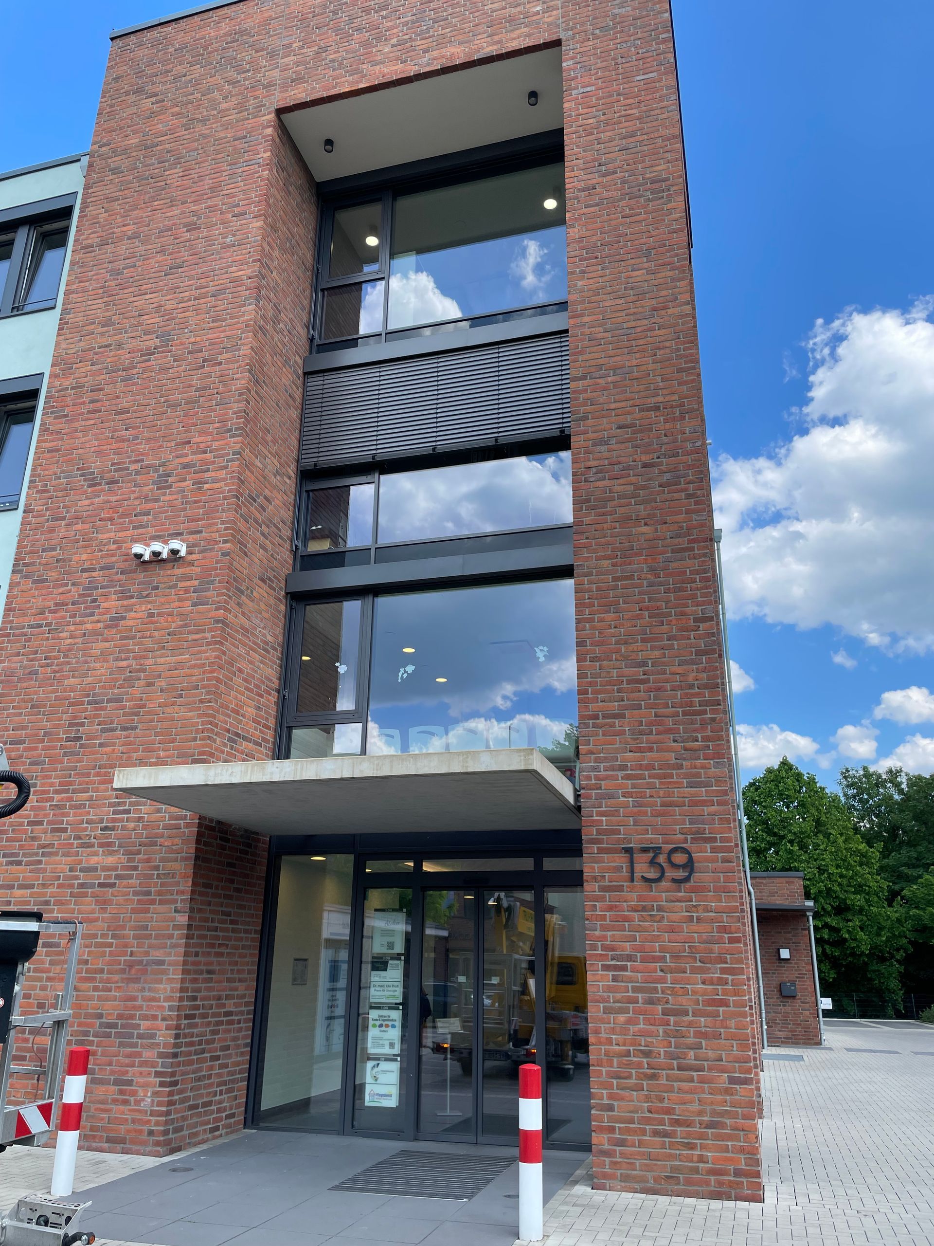 Backsteinfassade mit Balkon und schwarzem Lamellengeländer