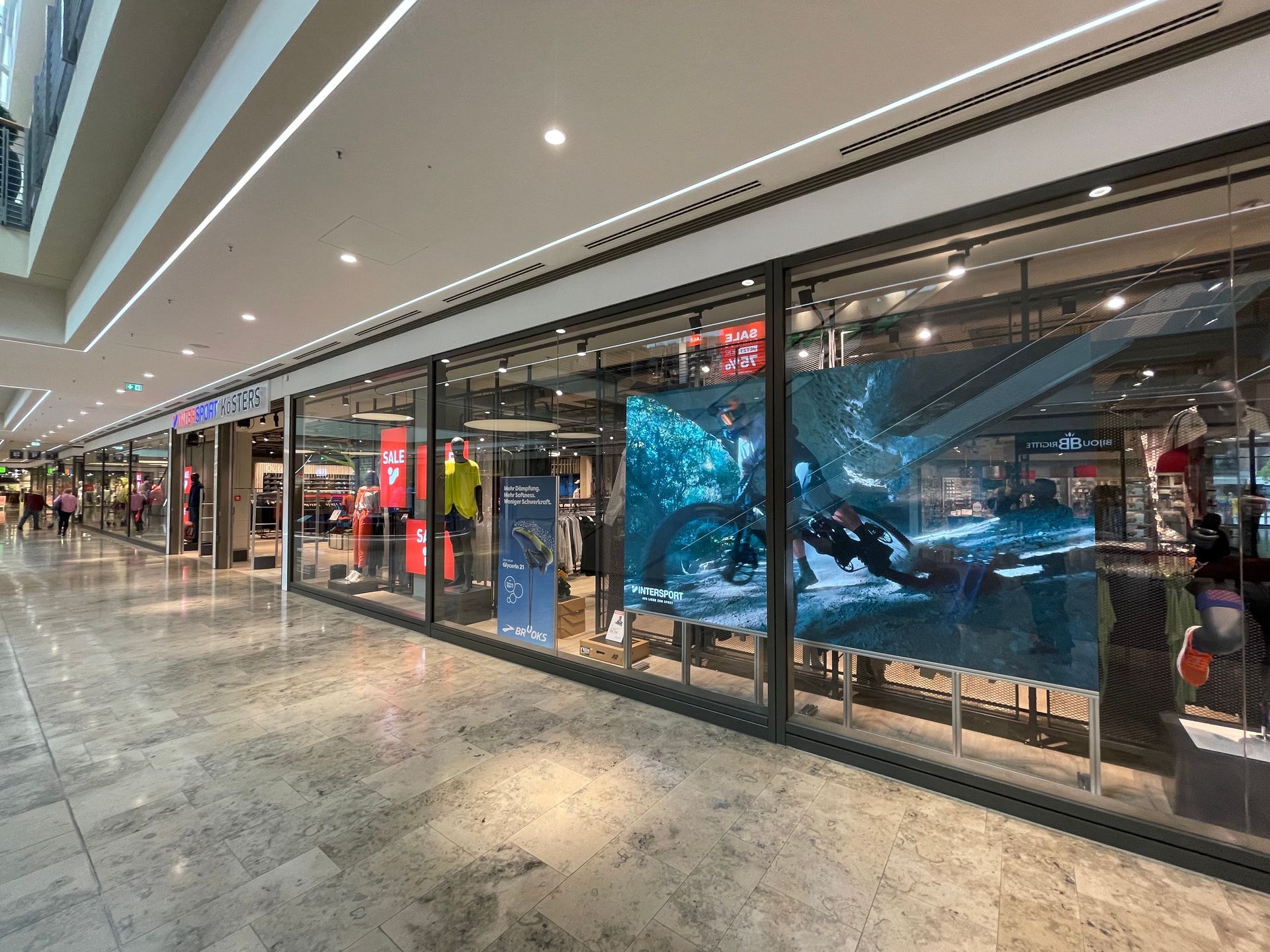Ladenfront mit großen Glasfenstern, darin ein großes Bildschirmbild eines Mountainbikers in Aktion.