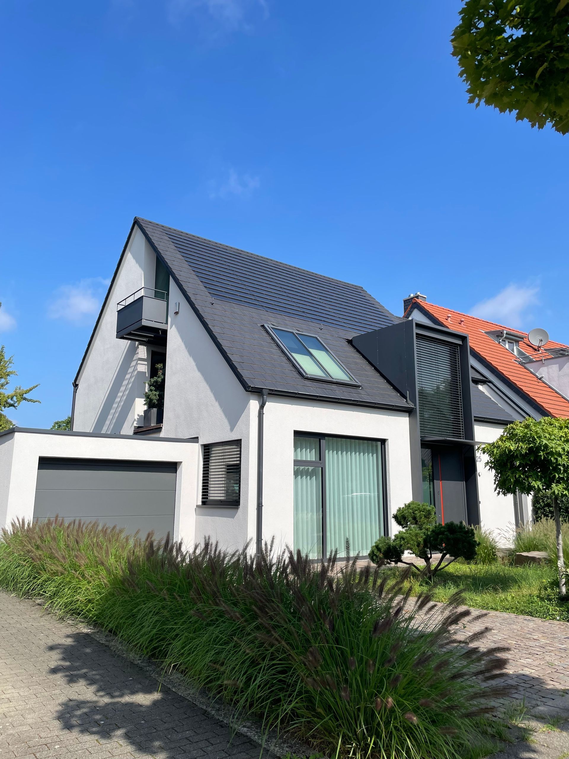 Steildachhaus mit dunklen Dachziegeln vor blauem Himmel