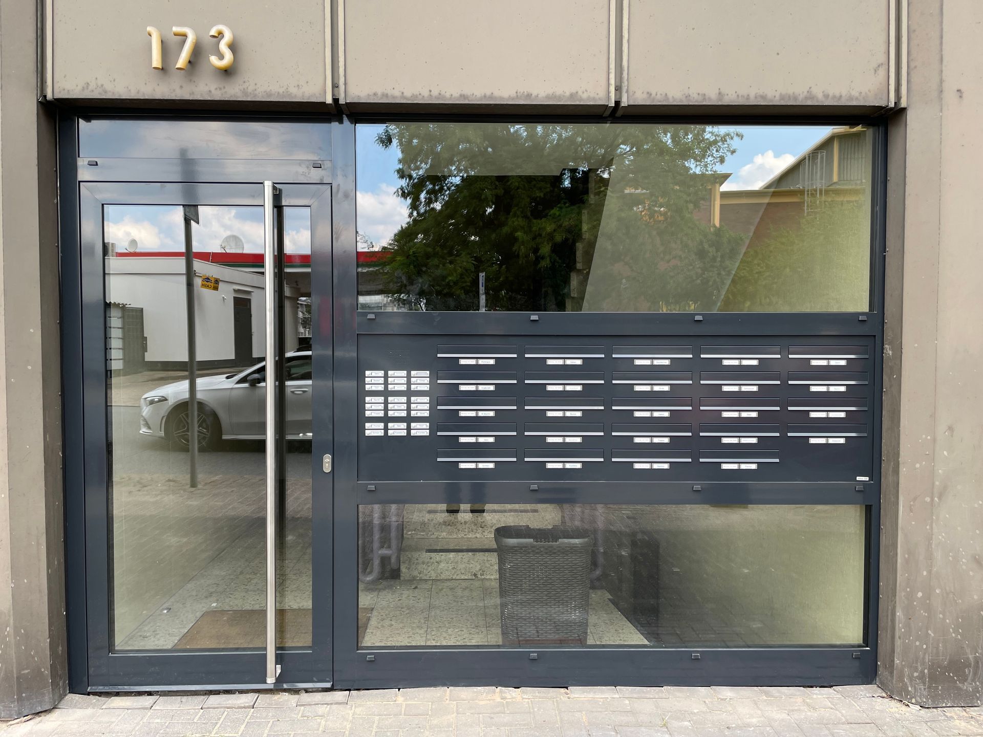 Hausfassade mit verglastem Eingang und mehreren Briefkästen