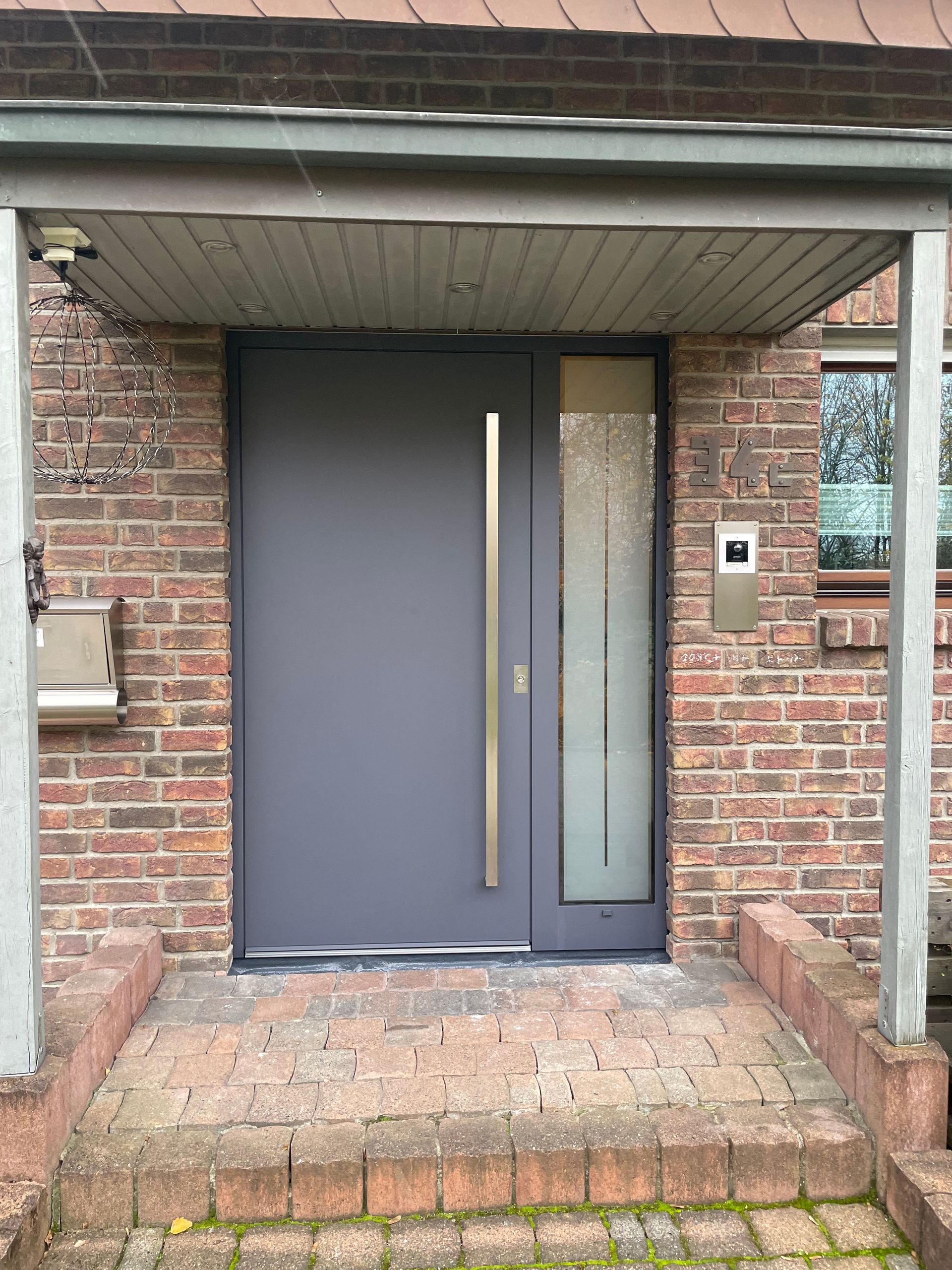 Überdachter Hauseingang mit dunkler Tür und Backsteinfassade