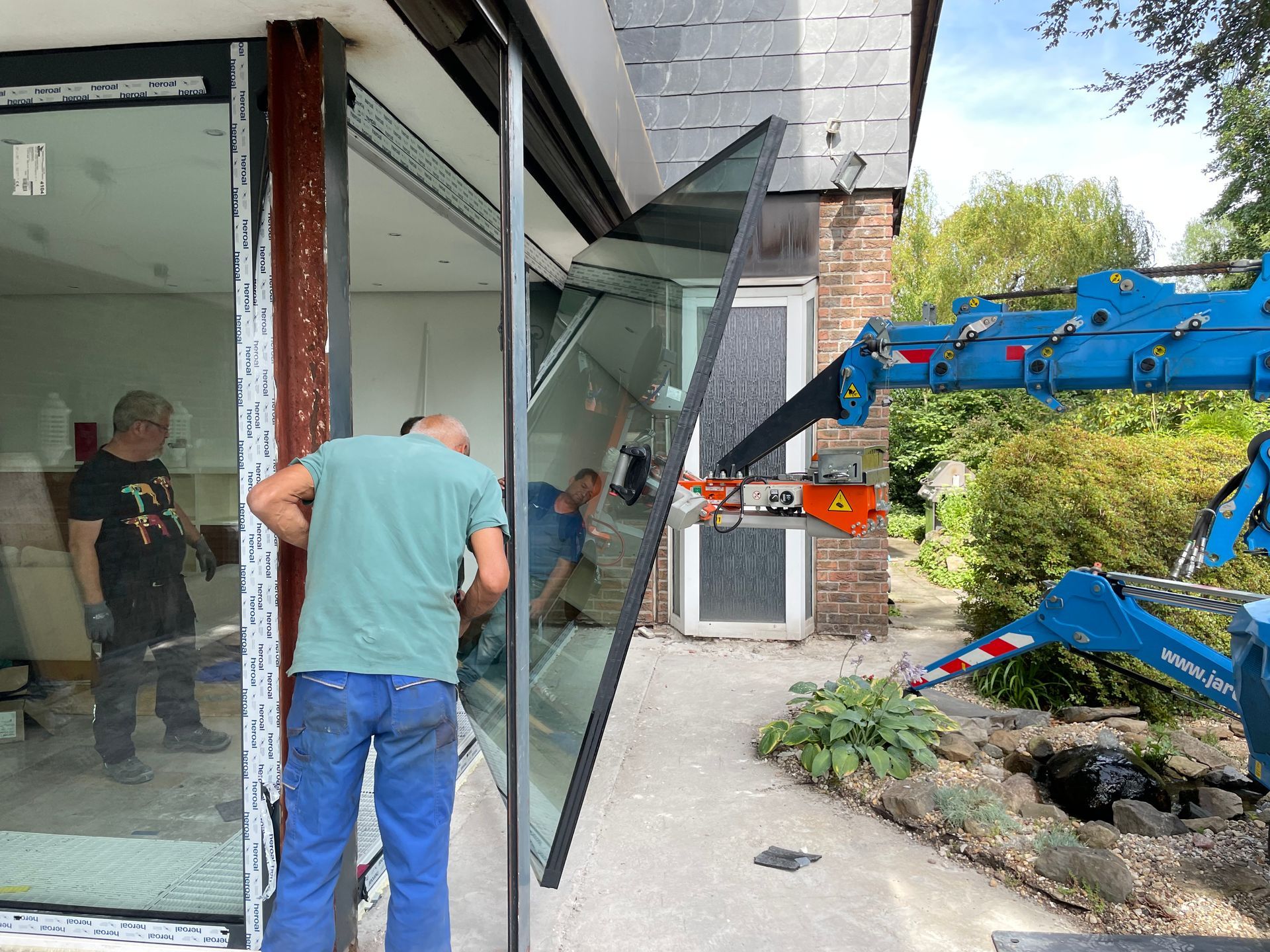 Arbeiter bei der Installation eines großen Fensters mit einem Kran
