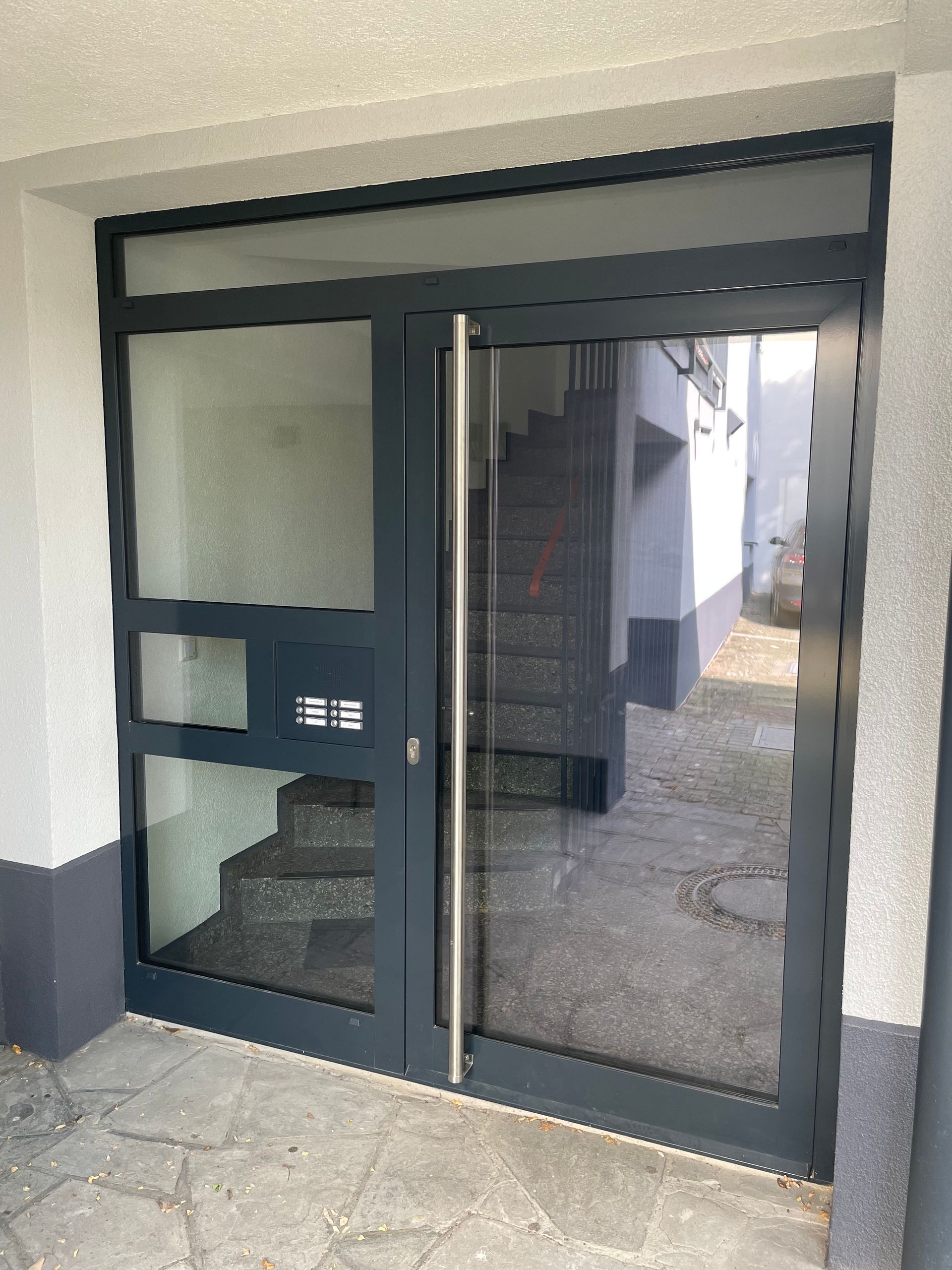 Eingangsbereich mit Glastür und seitlicher Metallabdeckung