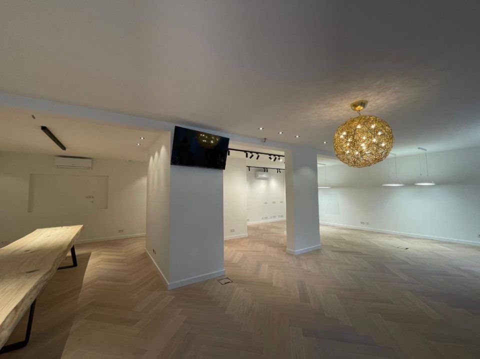 Ein großer leerer Raum mit einem Tisch und einem Kronleuchter, der von der Decke hängt. Tool Time NRW GmbH