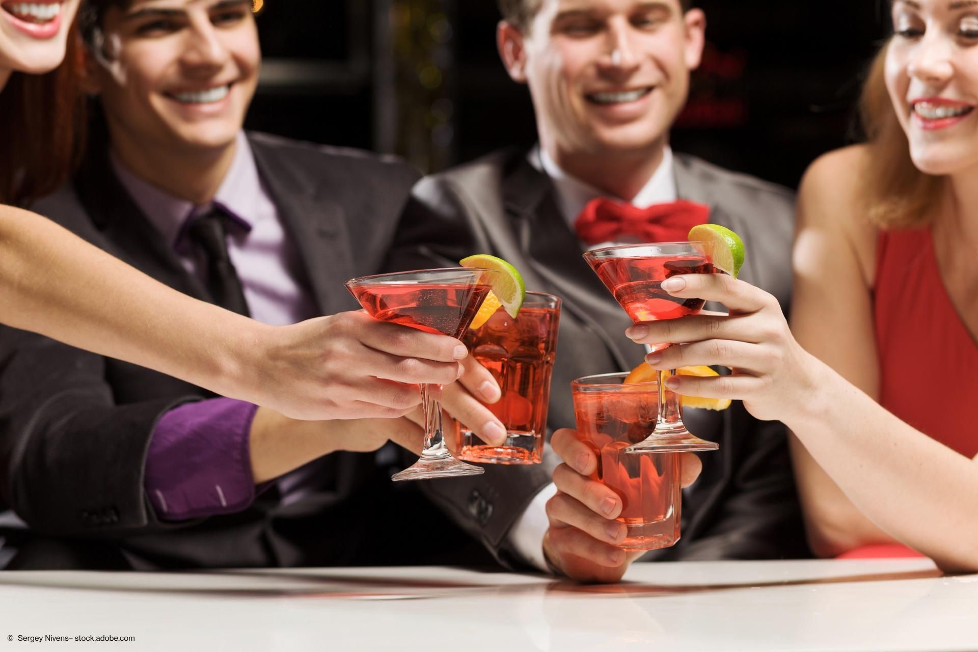Mehrere Menschen stoßen mit Cocktailgläsern an