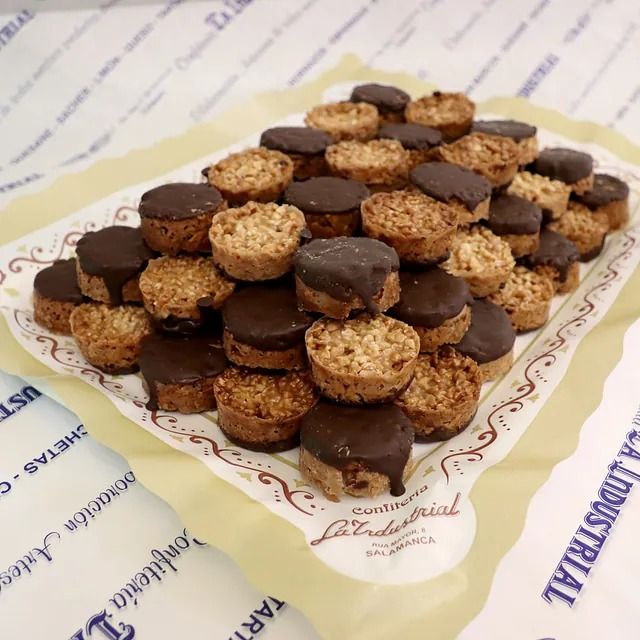 Una bandeja de galletas cubiertas de chocolate reposa sobre una mesa.