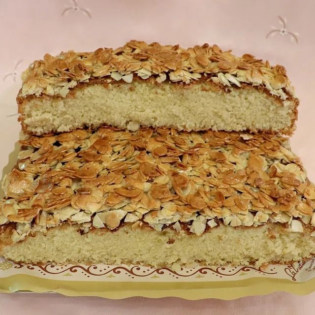 Un trozo de pastel con almendras encima se corta por la mitad.