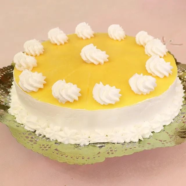Un pastel amarillo y blanco con crema batida encima.