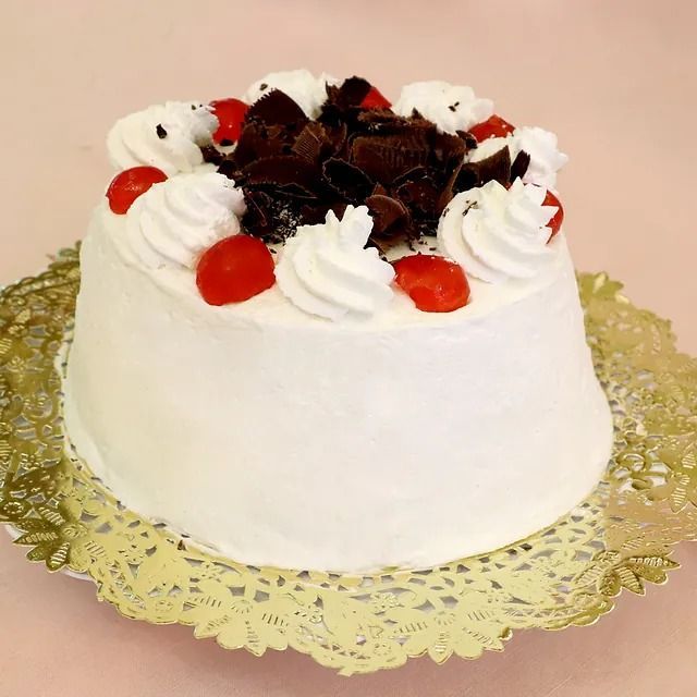 Un pastel blanco con crema batida y fresas encima.