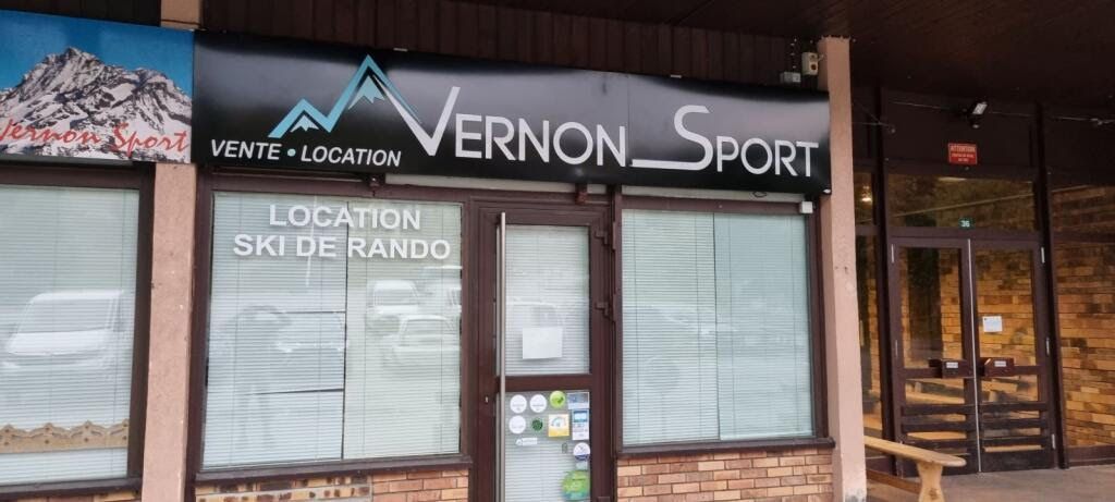 Façade du magasin Vernon Sport présentant une enseigne pour la vente et la location de matériel de ski dans un cadre de ville de montagne.