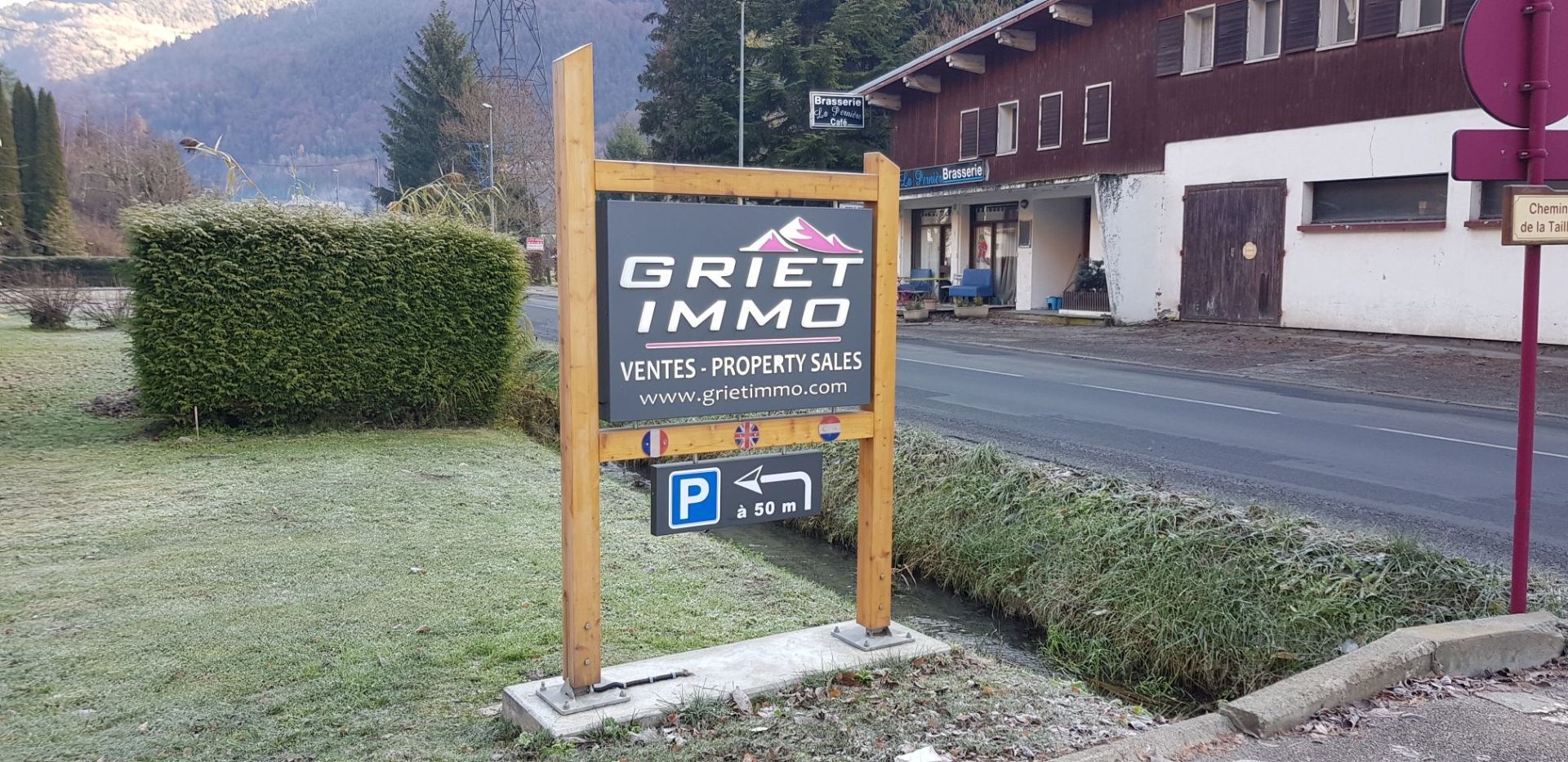 Panneau en bois pour l'agence immobilière Griet Immo, symbole de stationnement.
