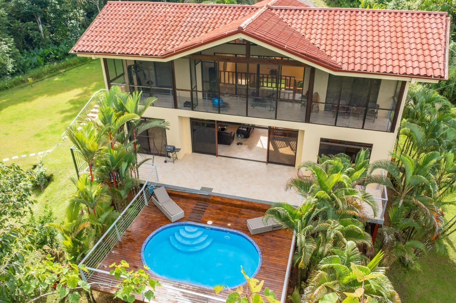 Modern two-story tropical house with big  balconies and beautiful pool surrounded by lush greenery