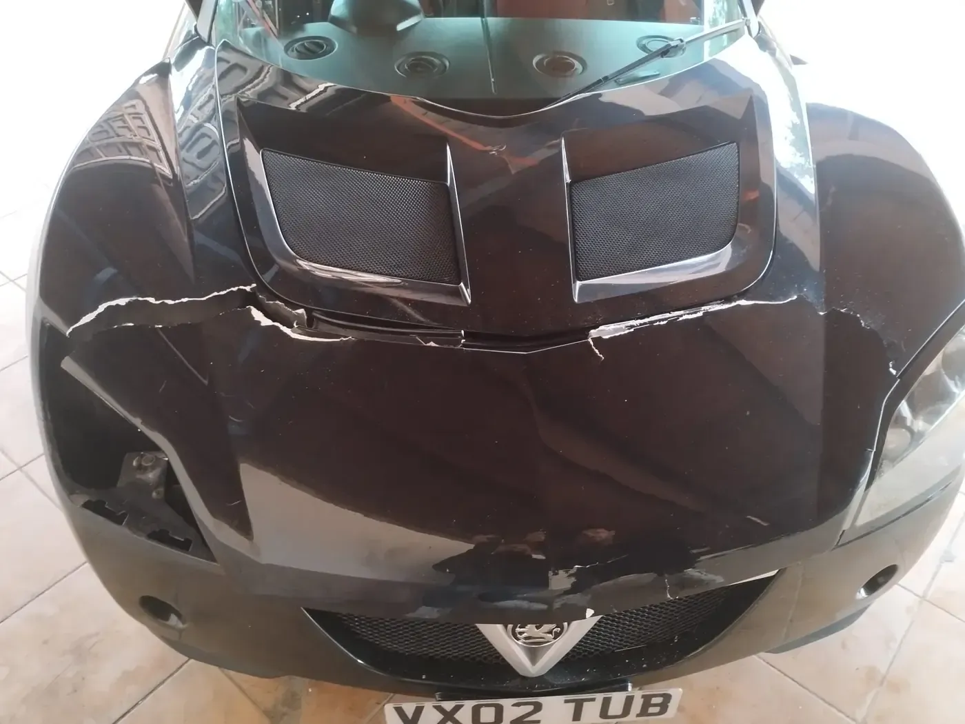 Gran tanque cilíndrico oxidado tirado al aire libre, con una escalera apoyada sobre él y un campo amarillo en el fondo.