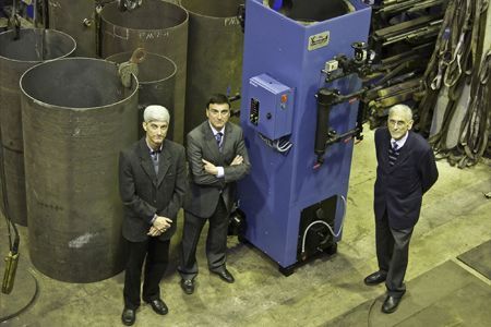 Tres hombres están parados frente a una gran máquina azul.