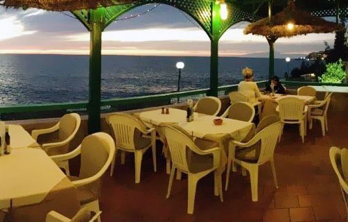 Un restaurante con mesas y sillas con vista al mar.