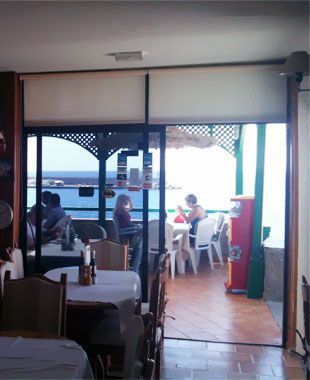 Un restaurante con mesas y sillas y vista al mar.