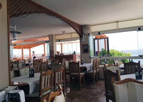 Un restaurante con mesas y sillas y vista al mar.