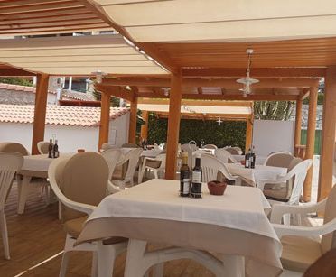 Un restaurante con mesas y sillas y botellas de vino sobre ellas.