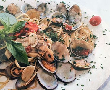 Un primer plano de un plato de comida con almejas y fideos en una mesa.
