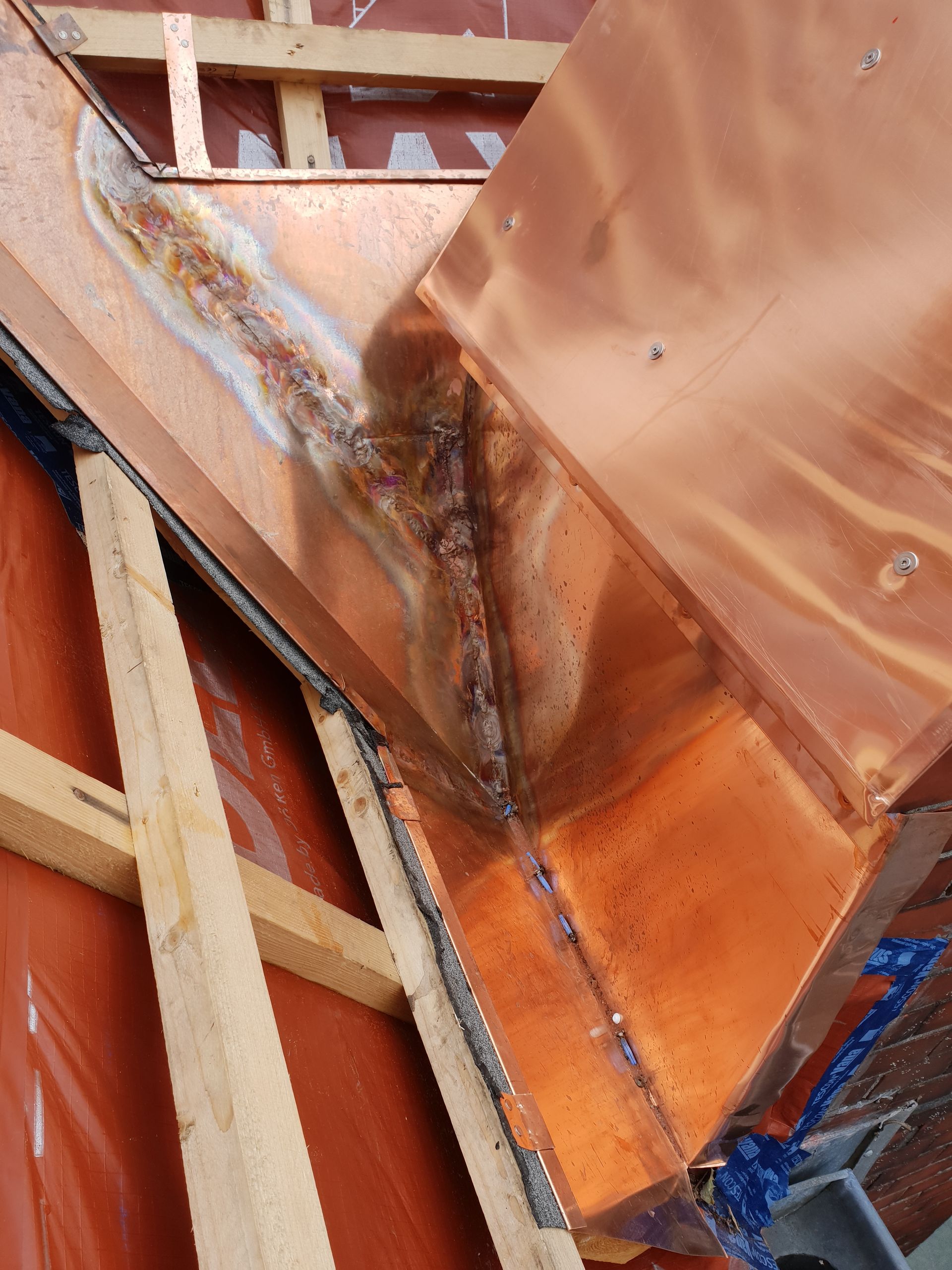 Rostorangefarbene Metallkonstruktion mit geschweißten Nähten und verwittertem Holzrahmen.