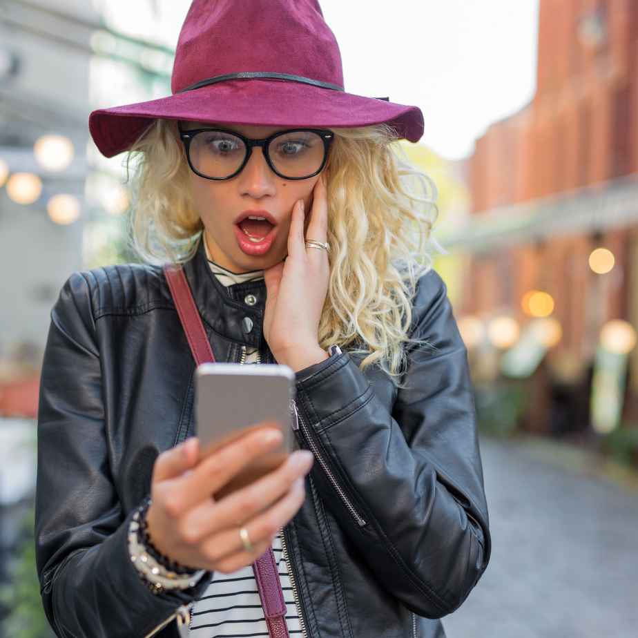 A woman wearing a purple hat and glasses is looking at her phone