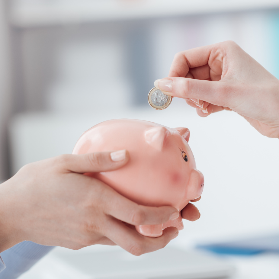 A person is putting a coin into a piggy bank.