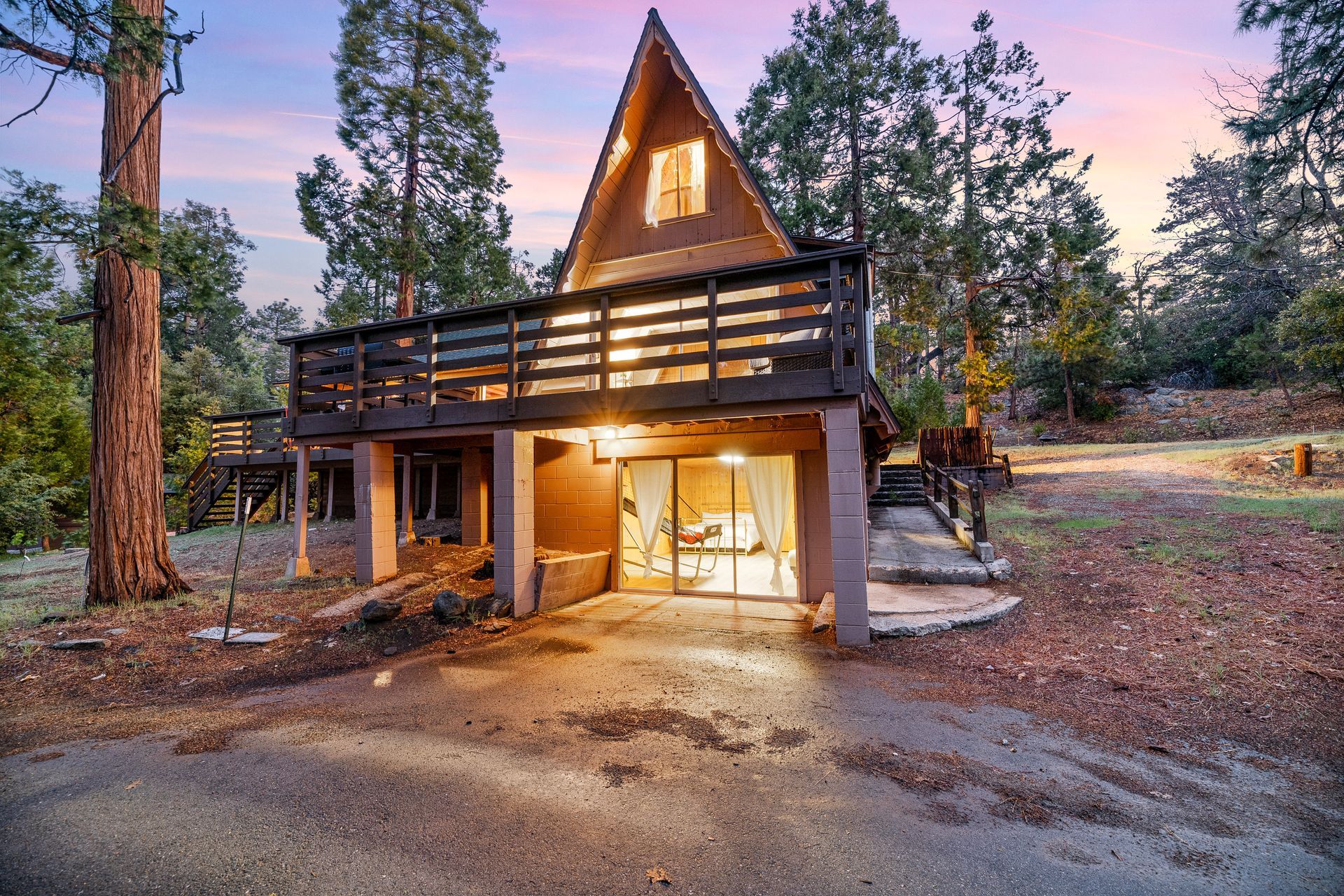 A small house with a deck is surrounded by trees at night.