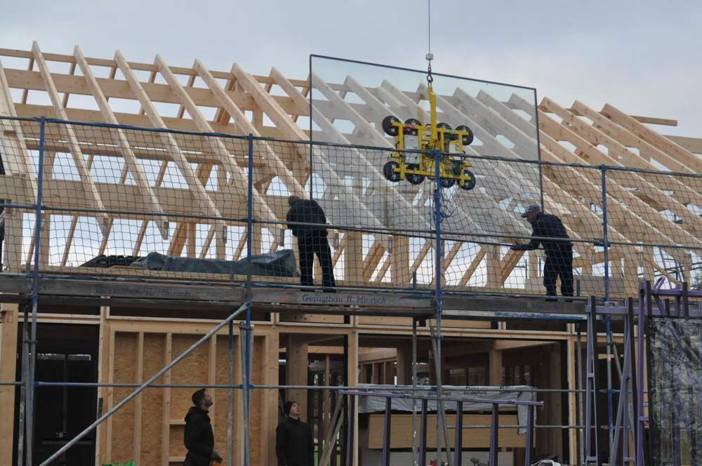 Bauarbeiter installieren auf einer Baustelle große Glasscheiben mit Saugnäpfen.