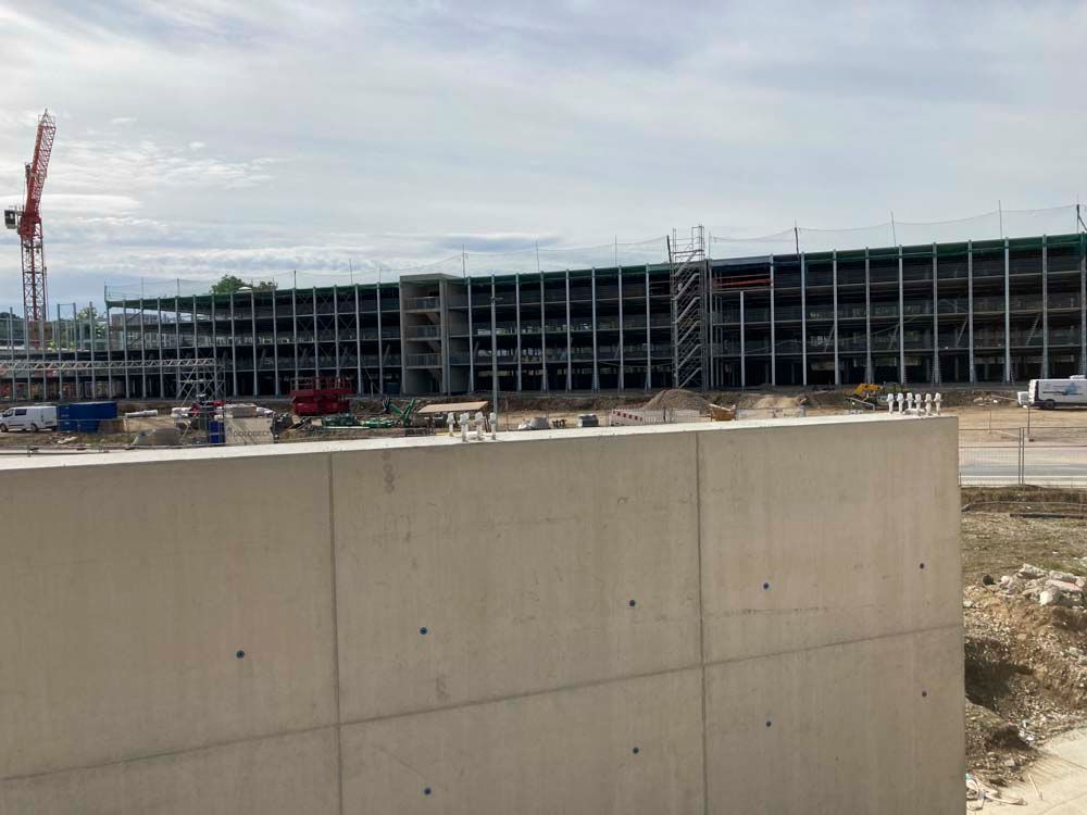 Baustelle mit mehrstöckigem Parkhaus und Kran.