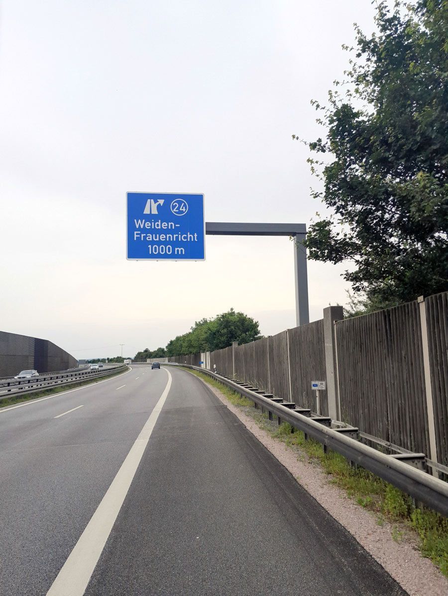 Ein blaues Schild am Straßenrand zeigt die Entfernung zu einer Stadt an