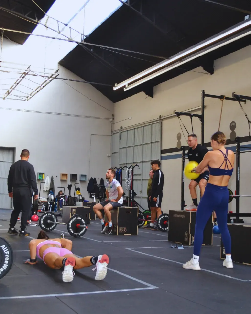 Personas haciendo ejercicio en un gimnasio. Una mujer de azul sostiene un balón;