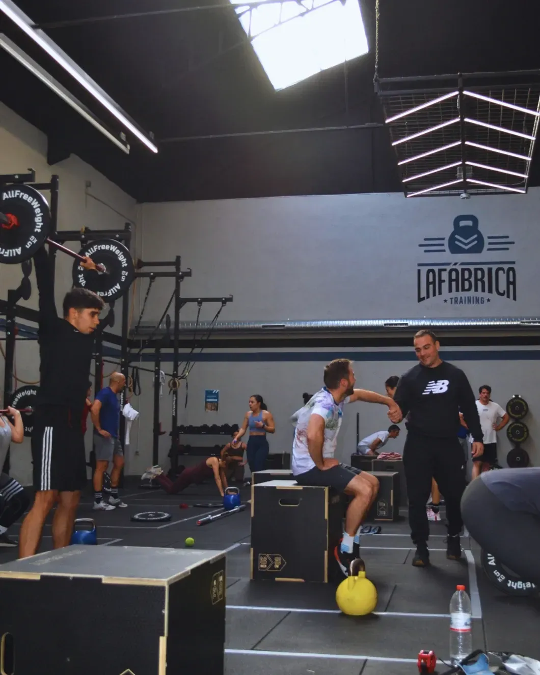 Personas haciendo ejercicio en un gimnasio. Una persona realiza un levantamiento de pesas. 